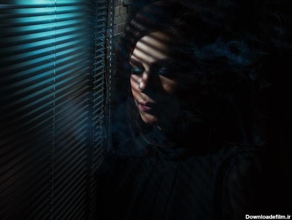 زن غمگین در پشت پنجره و تابش نور بر چهره زن 1644996