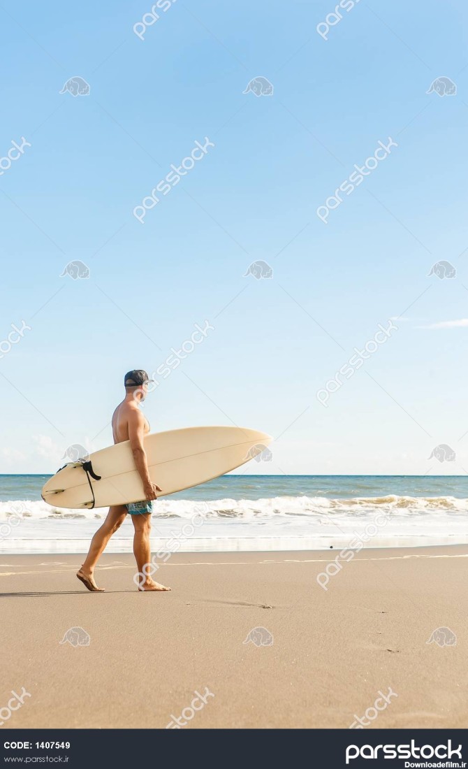 مرد با تخته موج سواری در کنار ساحل دریا در تابستان 1407549