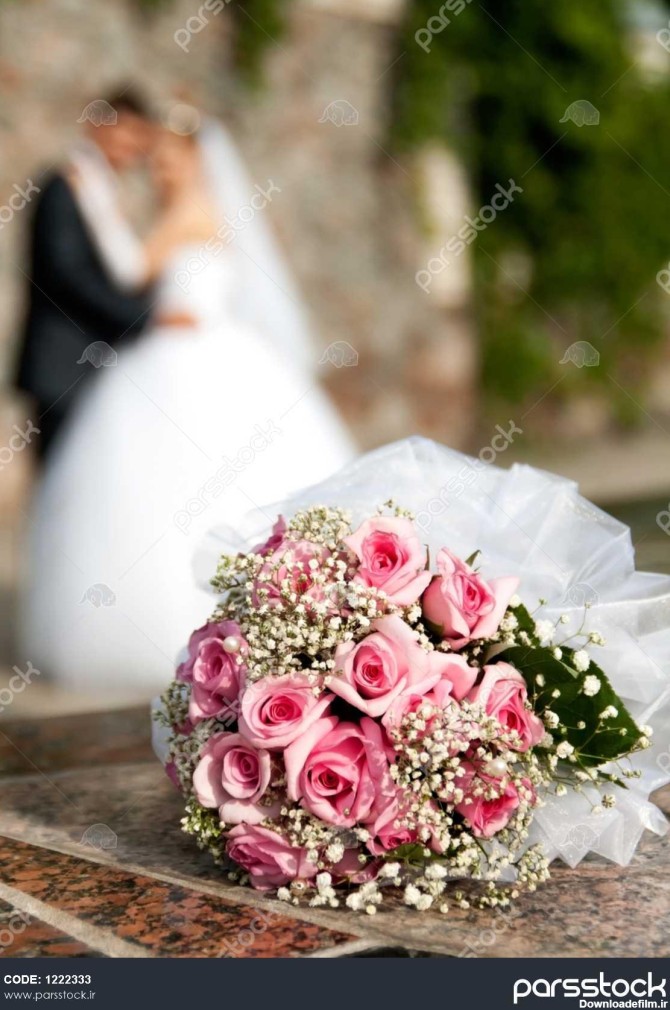 دسته گل رز روی پس زمینه داماد و عروس قرار دارد 1222333