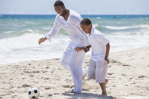 عکس با کیفیت پدر و پسر با لباس سفید لب ساحل در حال بازی با توپ jpeg