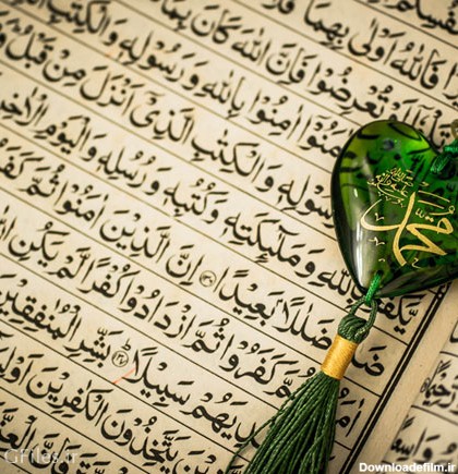 عکس قرآن باز با یک نشان قلب مانند سبز رنگ با نوشته ی محمد(ص)