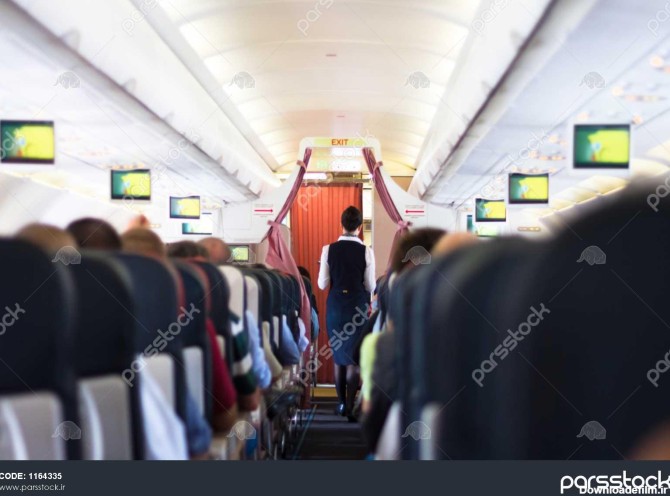 فضای داخلی هواپیما با مسافران روی صندلی و مهماندار که در ...