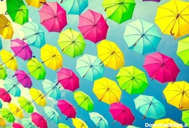 دانلود پس زمینه چشمه های رنگارنگ. چترهای رنگارنگ دکوراسیون خیابان شهری. چترهای رنگارنگ آویزان بر روی آسمان آبی. رنگ های روشن در پس زمینه