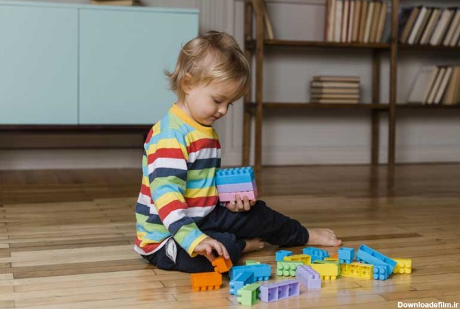 عکس با کیفیت پسر بچه در حال بازی با اسباب بازی خانه سازی