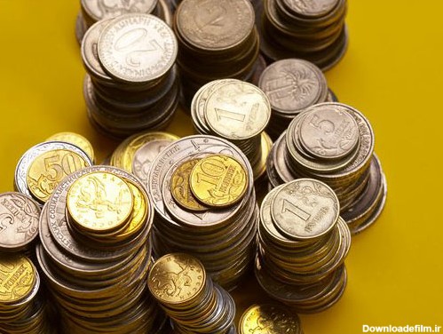 عکس با کیفیت از سکه های مختلف چیده شده روی هم با بکگراند زرد
